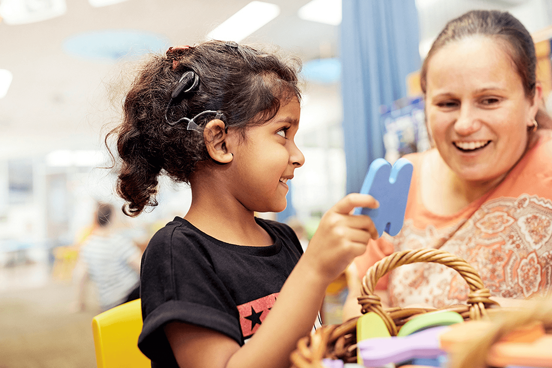 A child looking to the right at a smiling educator.
